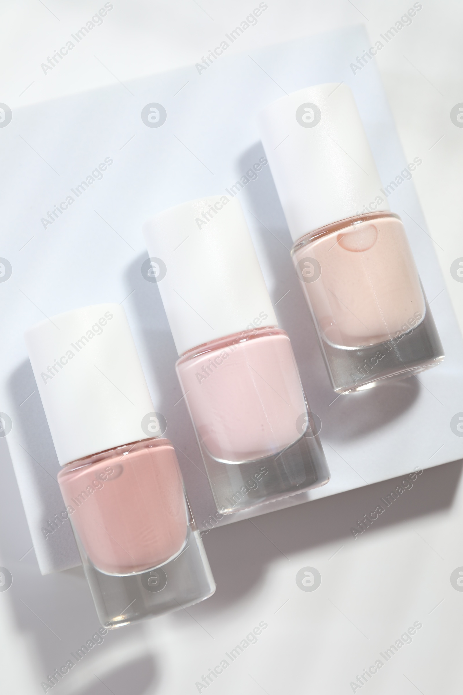 Photo of Nail polishes in bottles on white background, flat lay