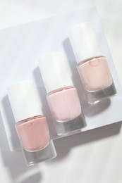 Photo of Nail polishes in bottles on white background, flat lay