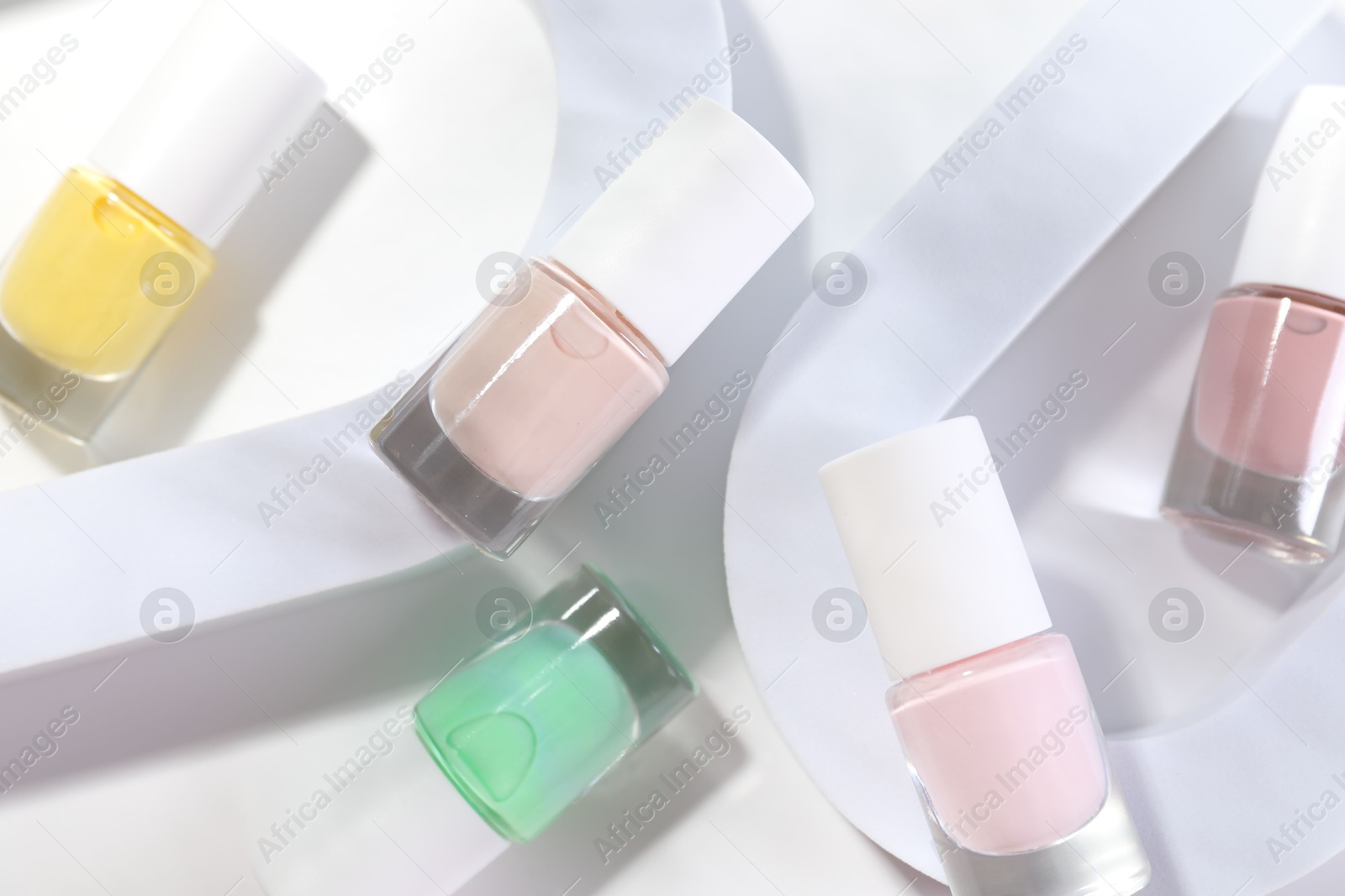 Photo of Nail polishes in bottles on white background, flat lay