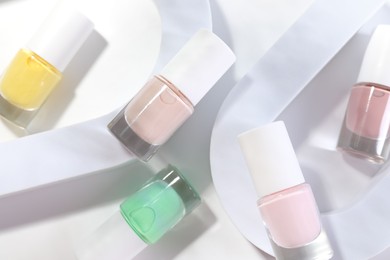 Photo of Nail polishes in bottles on white background, flat lay