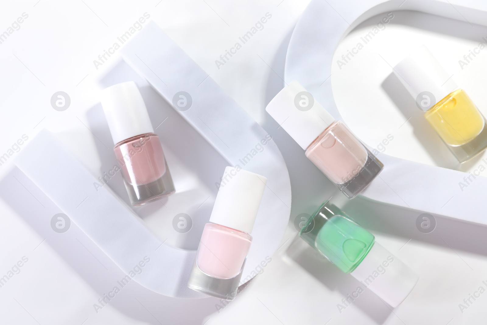 Photo of Nail polishes in bottles on white background, flat lay