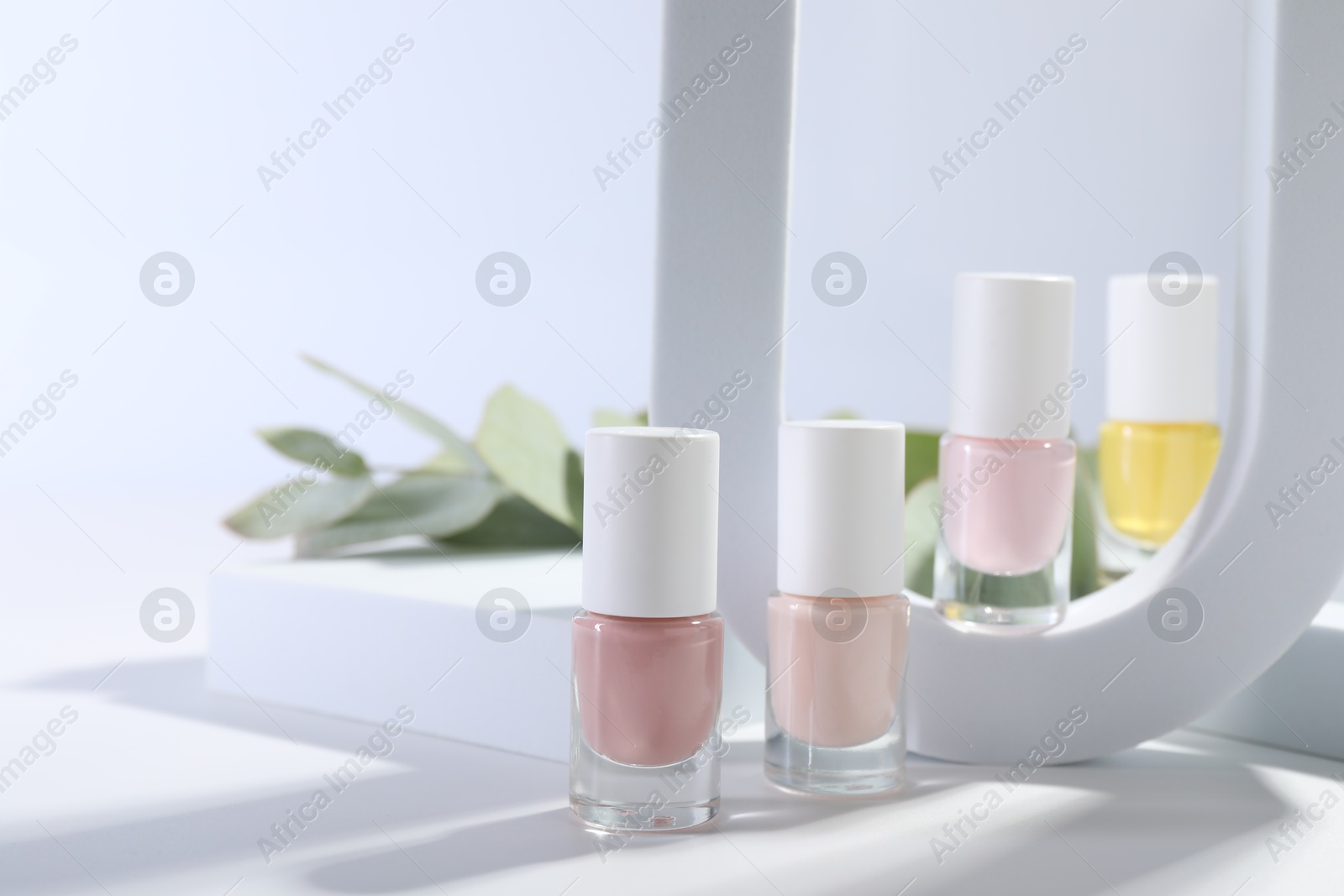 Photo of Stylish presentation of nail polishes in bottles on white table