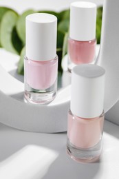 Photo of Stylish presentation of nail polishes in bottles on white table, closeup