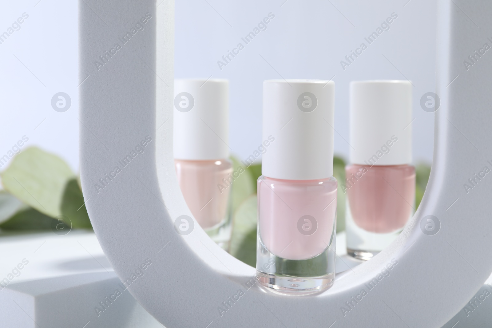 Photo of Stylish presentation of nail polishes in bottles on white background, closeup