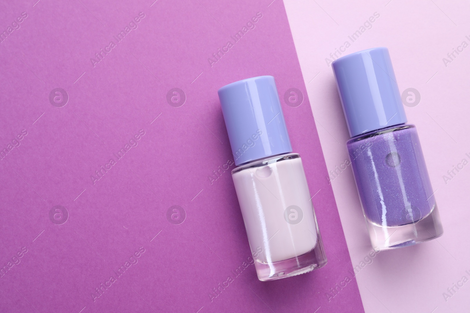 Photo of Nail polishes in bottles on color background, flat lay. Space for text