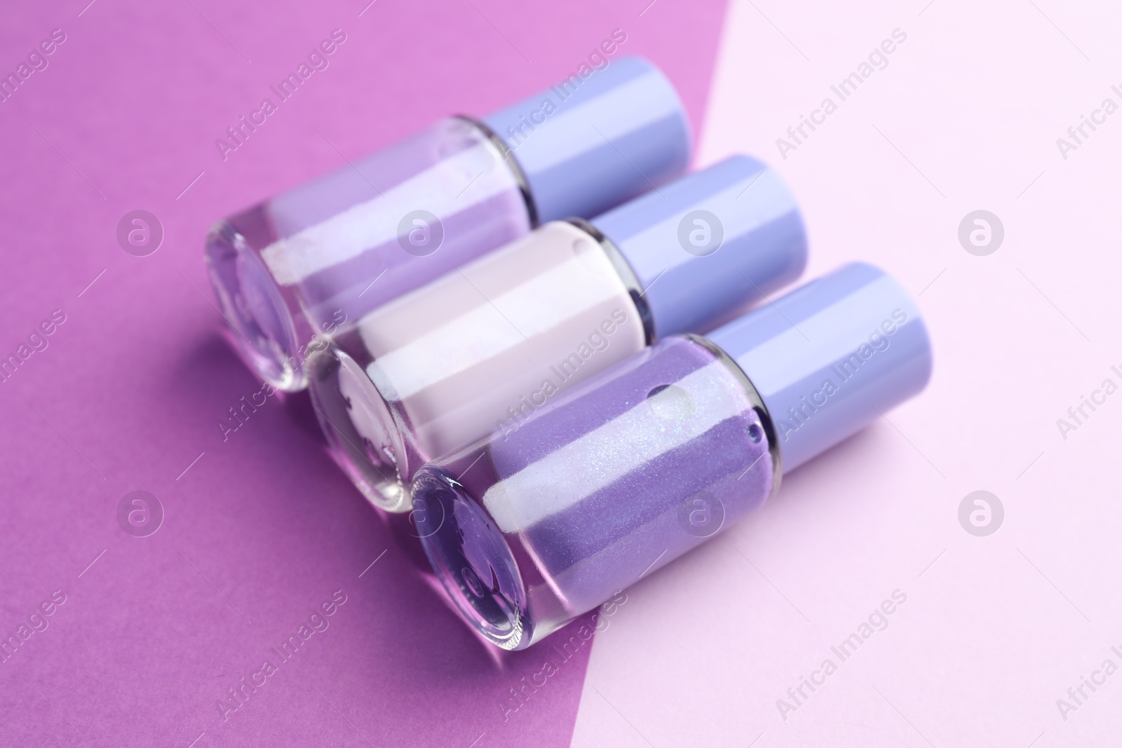 Photo of Nail polishes in bottles on color background, closeup