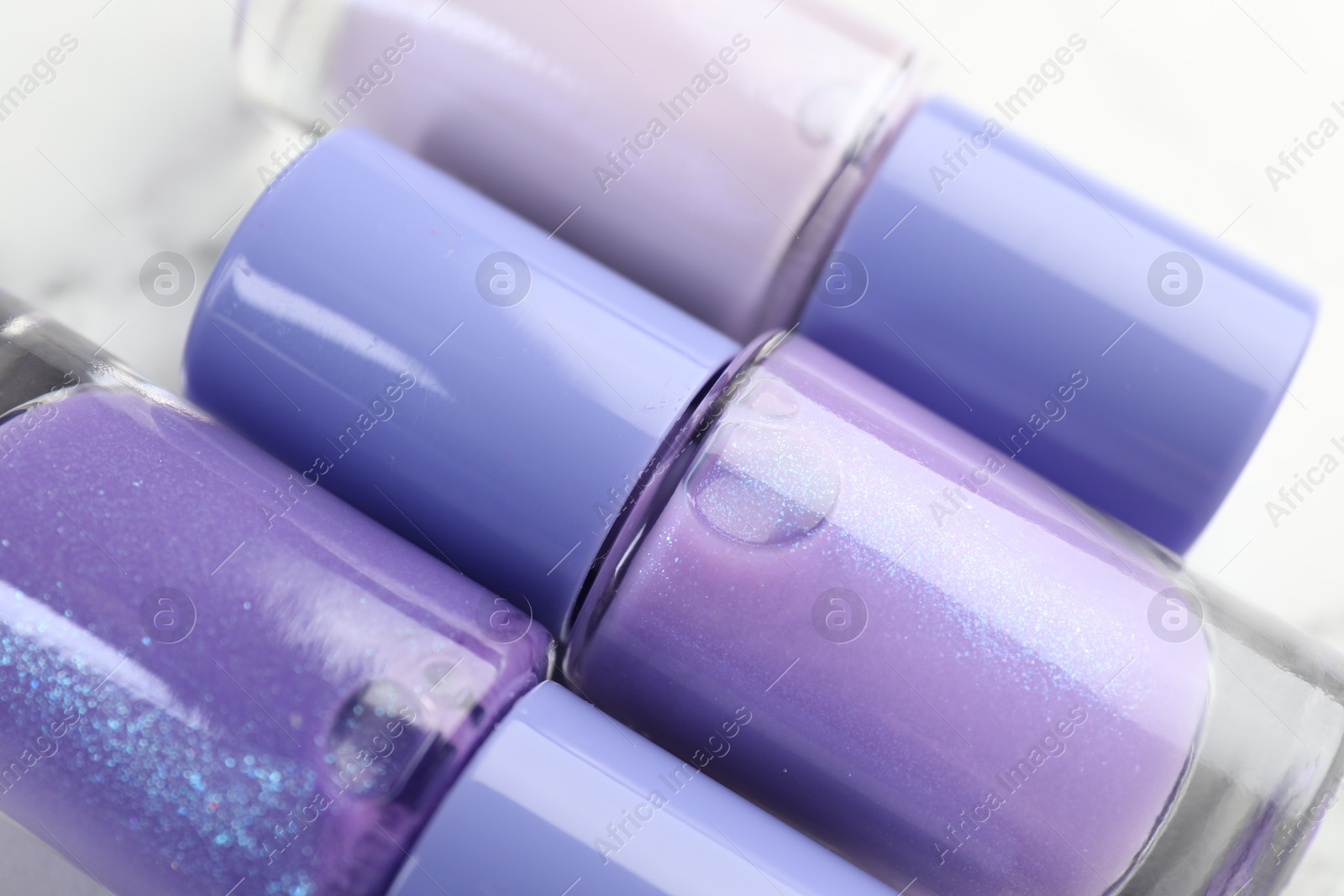 Photo of Nail polishes in bottles on white table, closeup