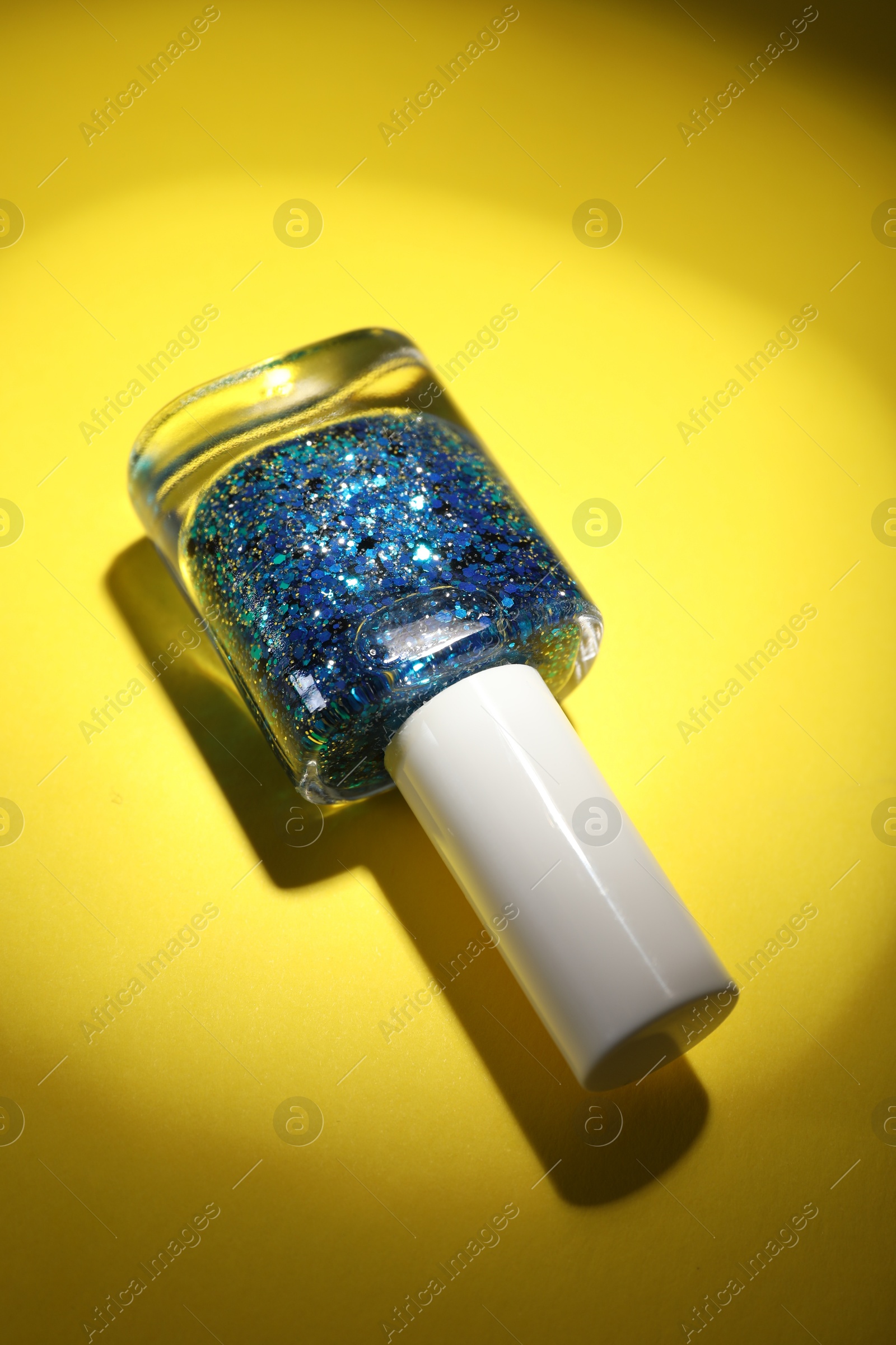 Photo of Nail polish in bottle on yellow background