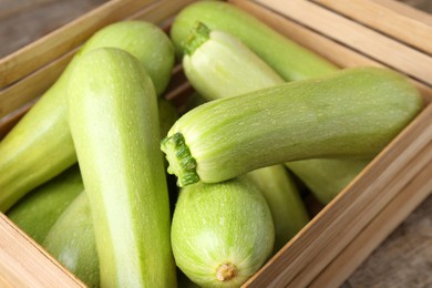 Photo of Crate with fresh zucchinis on wooden table, closeup