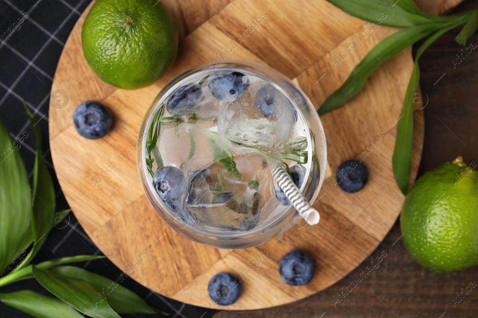 Photo of Refreshing water with blueberries and rosemary in glass on wooden table, flat lay