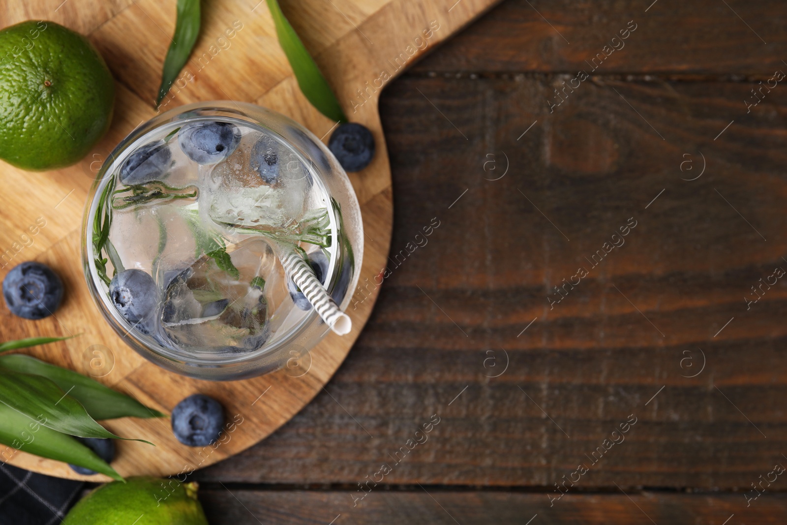 Photo of Refreshing water with blueberries and rosemary in glass on wooden table, flat lay. Space for text