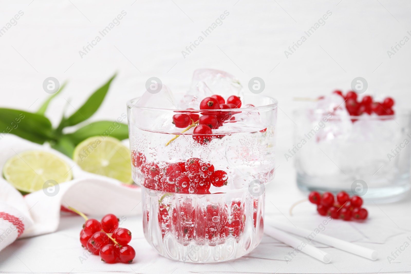 Photo of Refreshing water with red currants in glass on light table, closeup