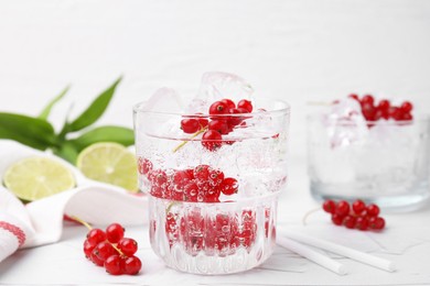 Refreshing water with red currants in glass on light table, closeup