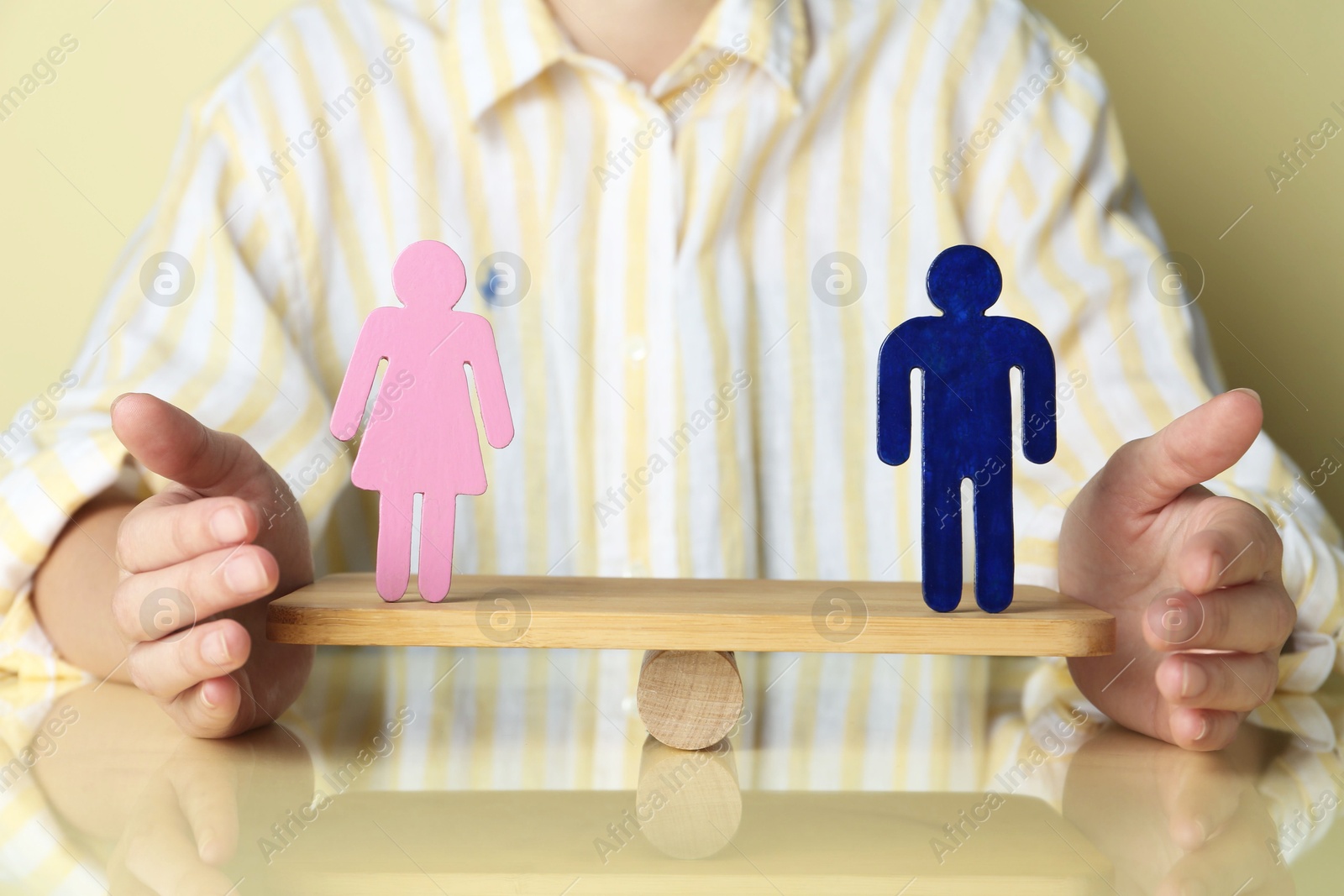 Photo of Gender equality concept. Woman with male and female figures on scales against light yellow background, closeup