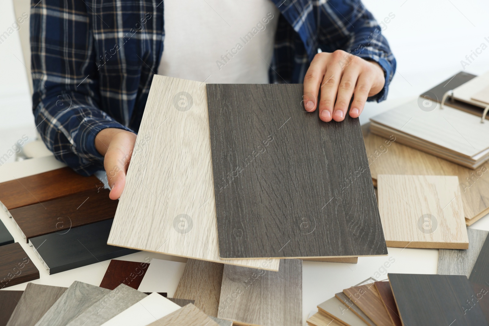 Photo of Man choosing wooden flooring among different samples at table, closeup