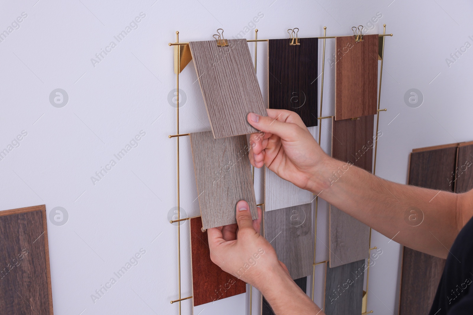 Photo of Man with different samples of wooden flooring indoors, closeup