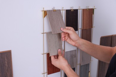 Photo of Man with different samples of wooden flooring indoors, closeup