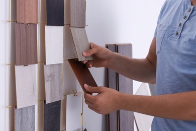 Photo of Man with different samples of wooden flooring indoors, closeup