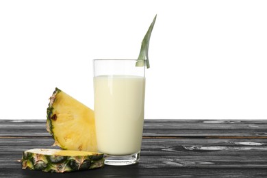 Photo of Tasty pineapple smoothie in glass and slices of fruit on wooden table against white background. Space for text