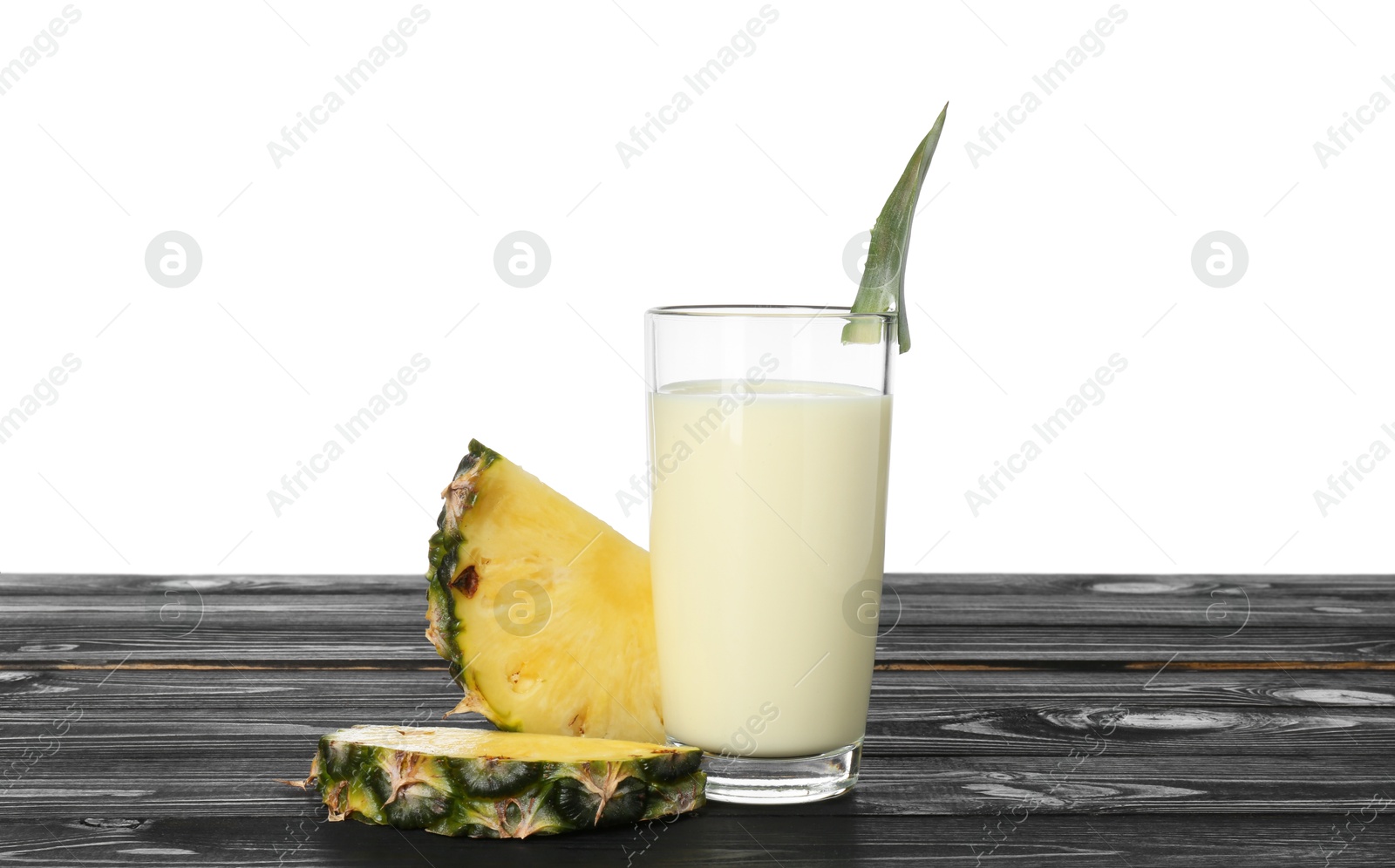 Photo of Tasty pineapple smoothie in glass and slices of fruit on wooden table against white background