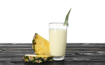 Photo of Tasty pineapple smoothie in glass and slices of fruit on wooden table against white background