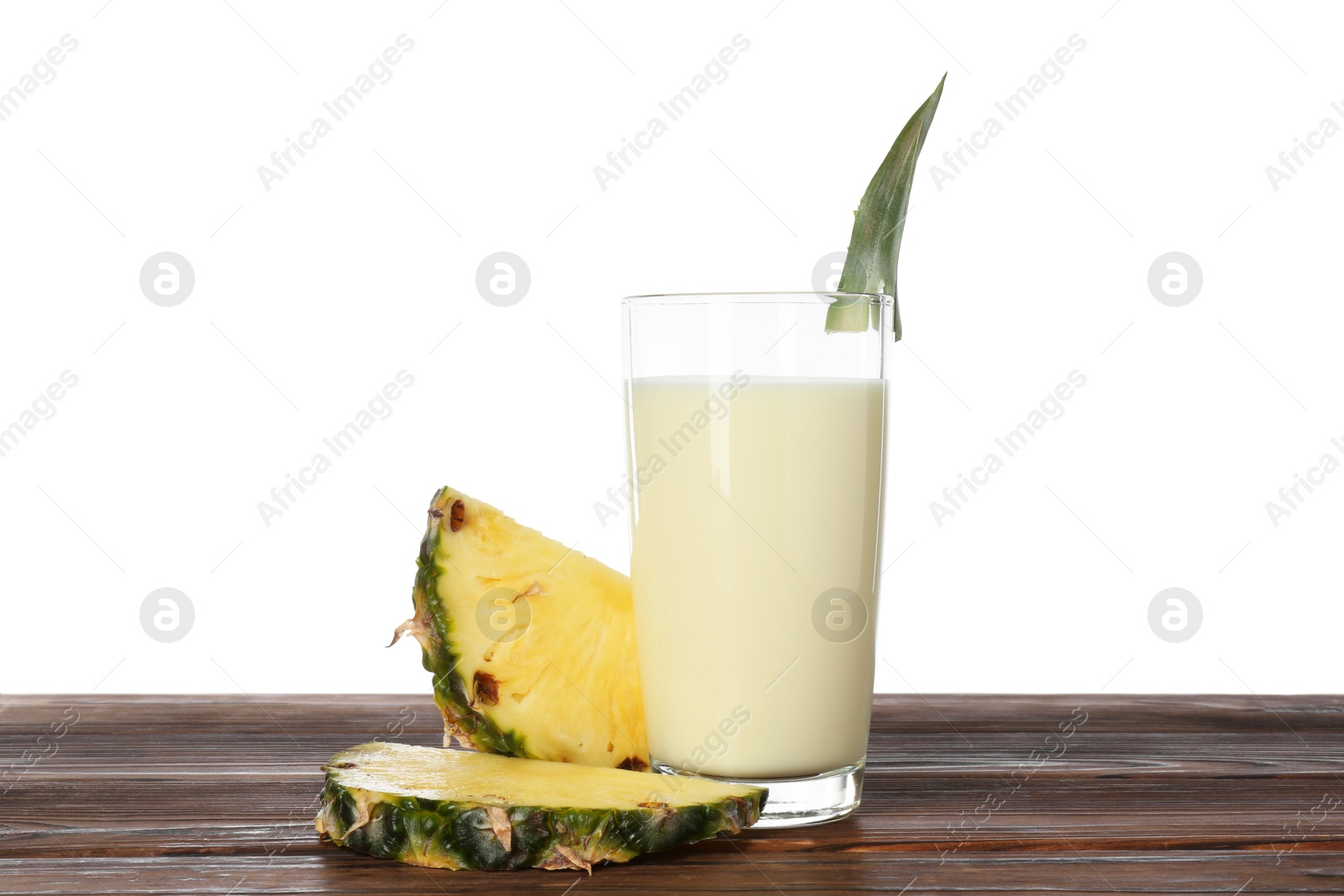 Photo of Tasty pineapple smoothie in glass and slices of fruit on wooden table against white background