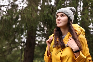 Young hiker with backpack in forest, space for text