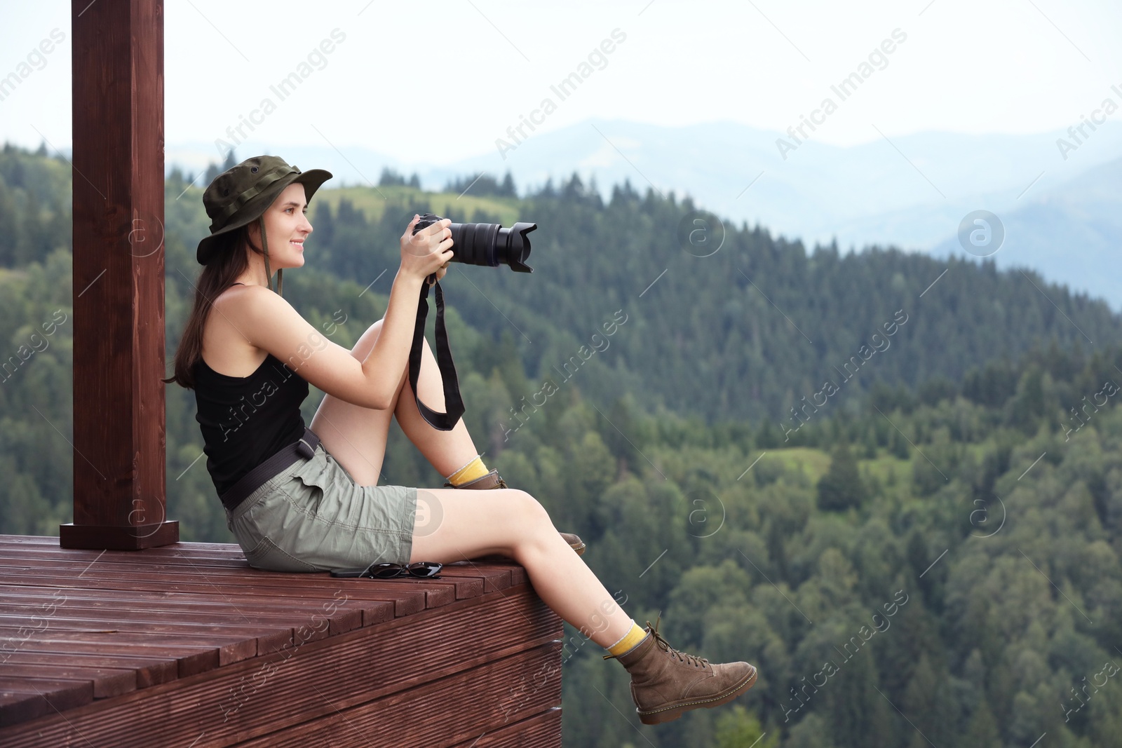 Photo of Young hiker with camera in mountains, space for text