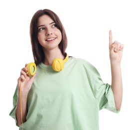 Portrait of cute teenage girl with headphones pointing at something on white background