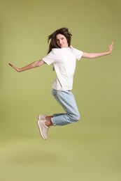 Photo of Cute teenage girl jumping on olive background