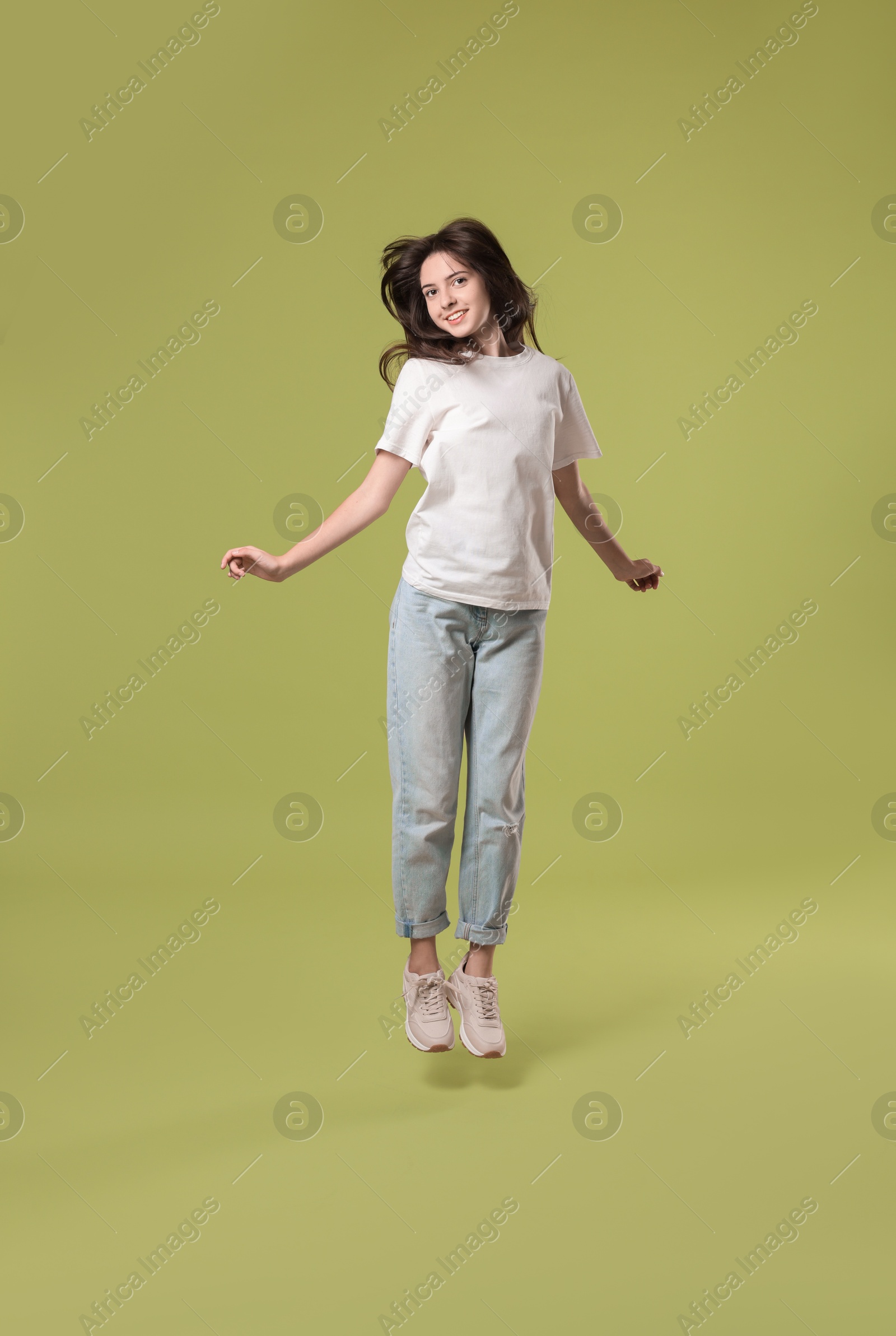 Photo of Cute teenage girl jumping on olive background