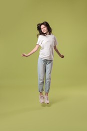 Cute teenage girl jumping on olive background