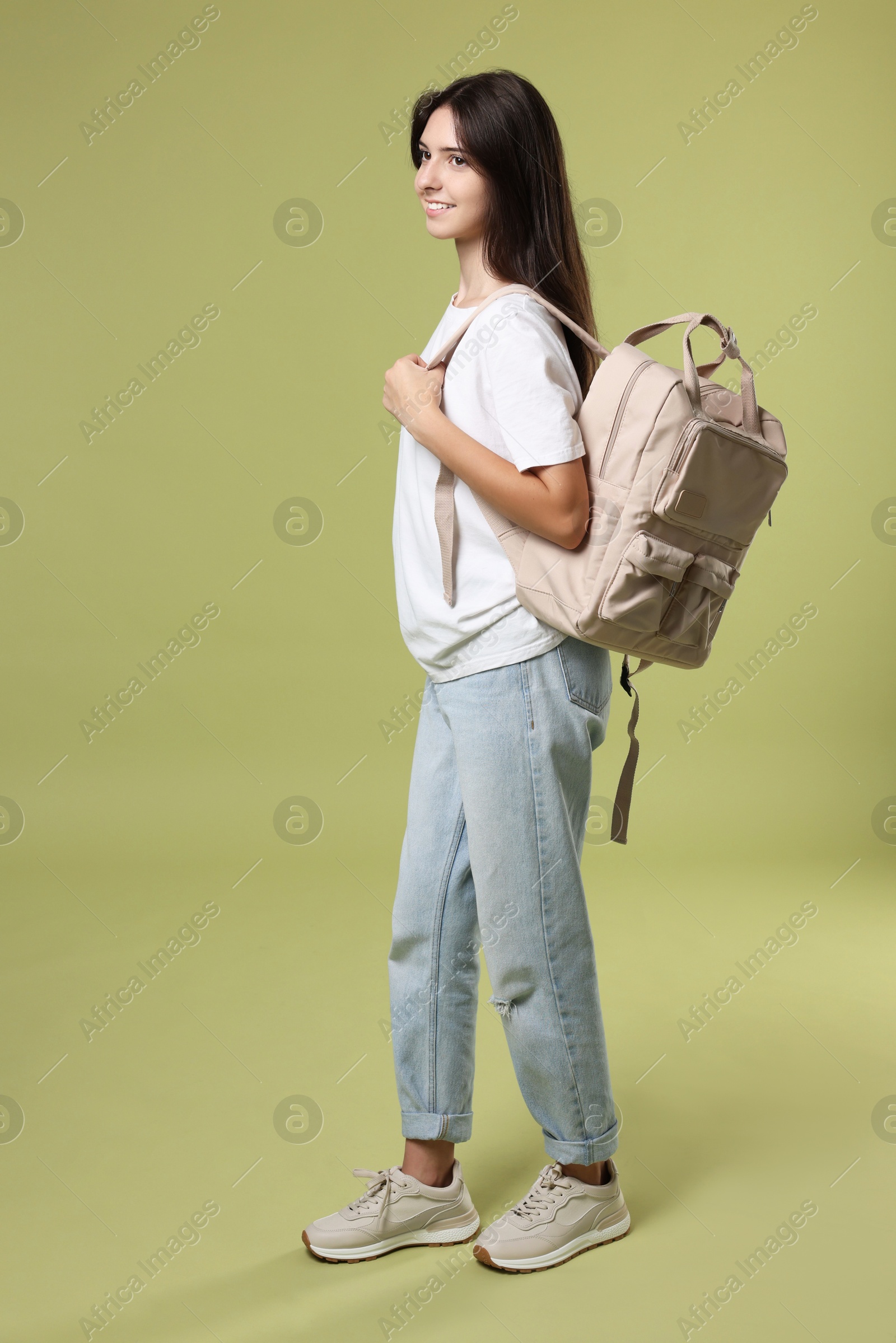 Photo of Cute teenage girl with backpack on olive background