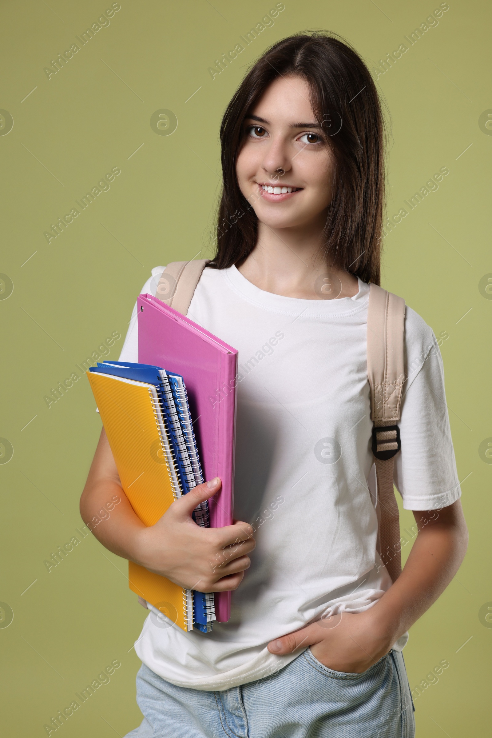 Photo of Portrait of cute teenage girl with backpack and books on olive background