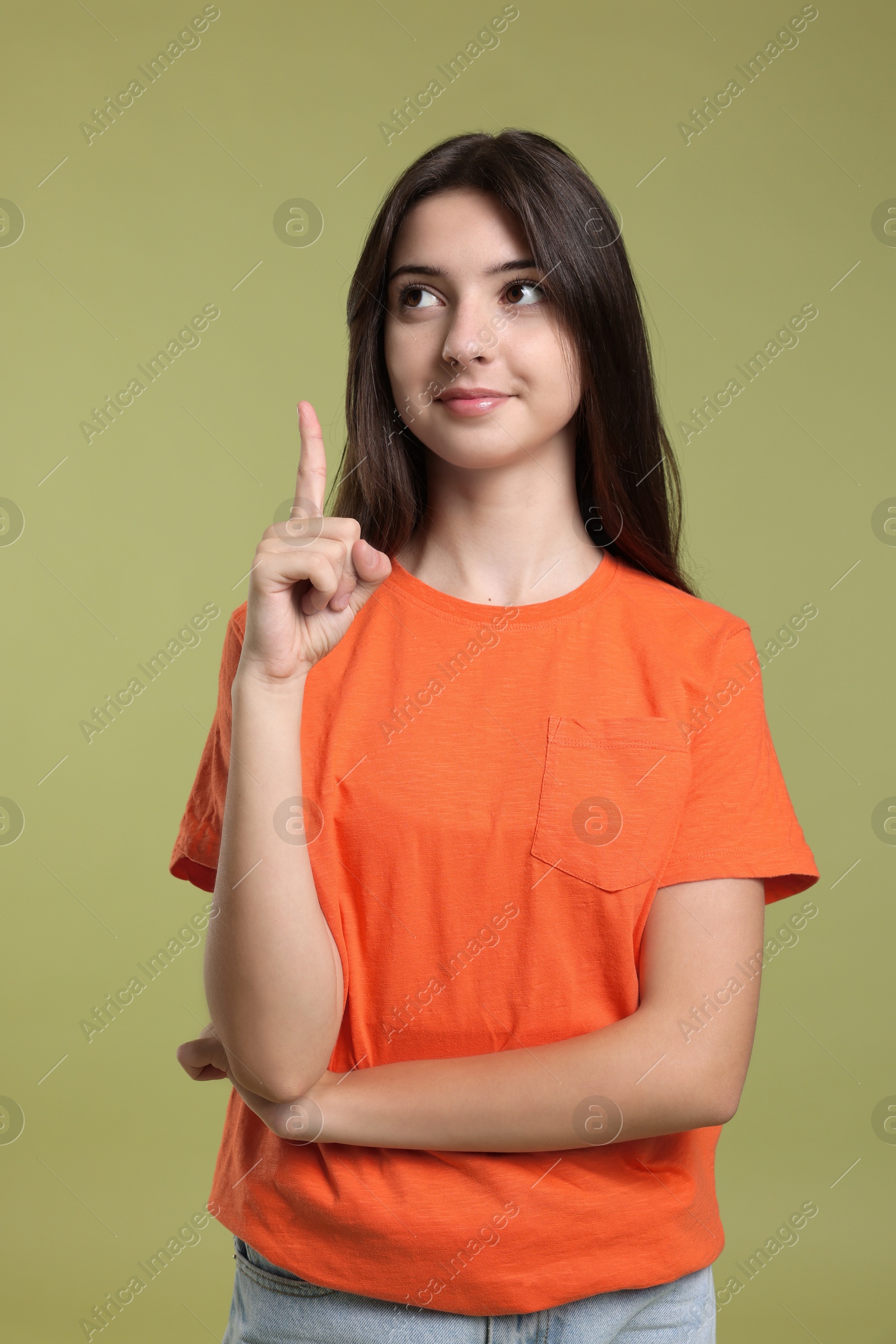 Photo of Portrait of cute teenage girl pointing at something on olive background