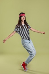 Full length portrait of cheerful teenage girl on olive background