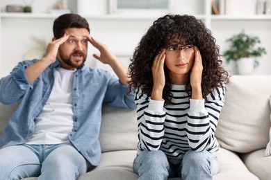 Photo of Emotional couple having quarrel on sofa at home, selective focus. Relationship problems