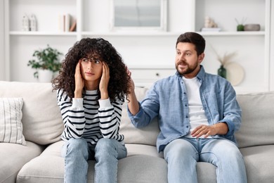 Photo of Emotional couple having quarrel on sofa at home, selective focus. Relationship problems