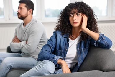 Photo of Emotional couple having quarrel on sofa at home, selective focus. Relationship problems