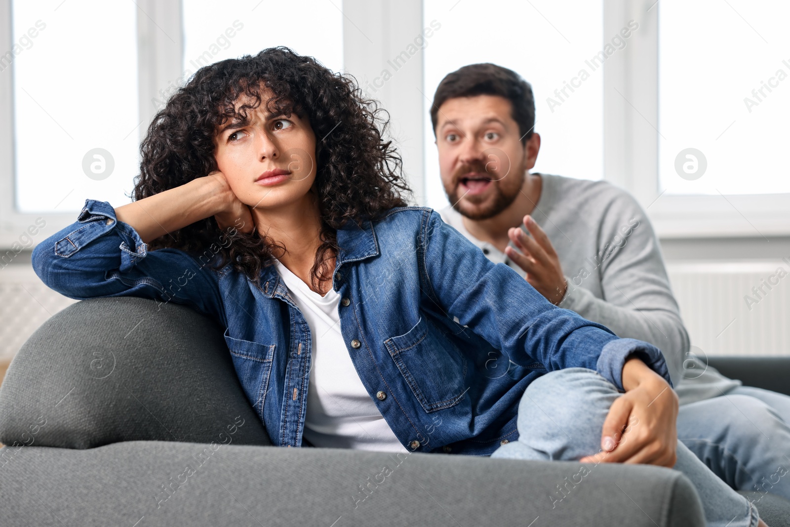 Photo of Emotional couple having quarrel on sofa at home, selective focus. Relationship problems