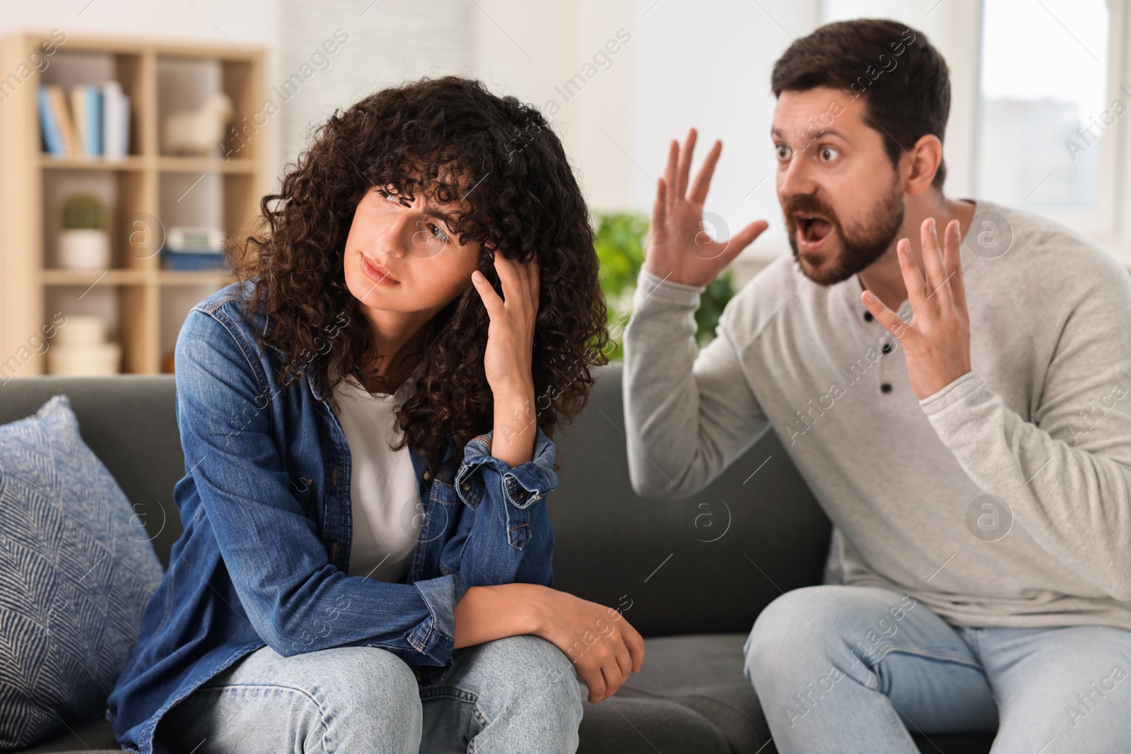 Photo of Emotional couple having quarrel on sofa at home, selective focus. Relationship problems