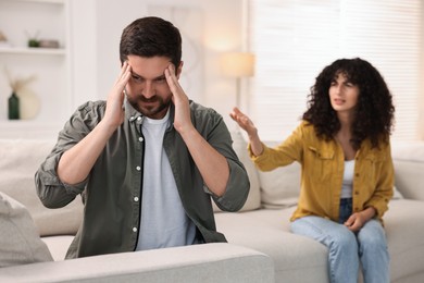 Photo of Couple having quarrel on sofa at home, selective focus. Relationship problems