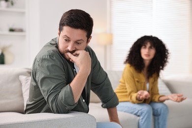 Photo of Couple having quarrel on sofa at home, selective focus. Relationship problems