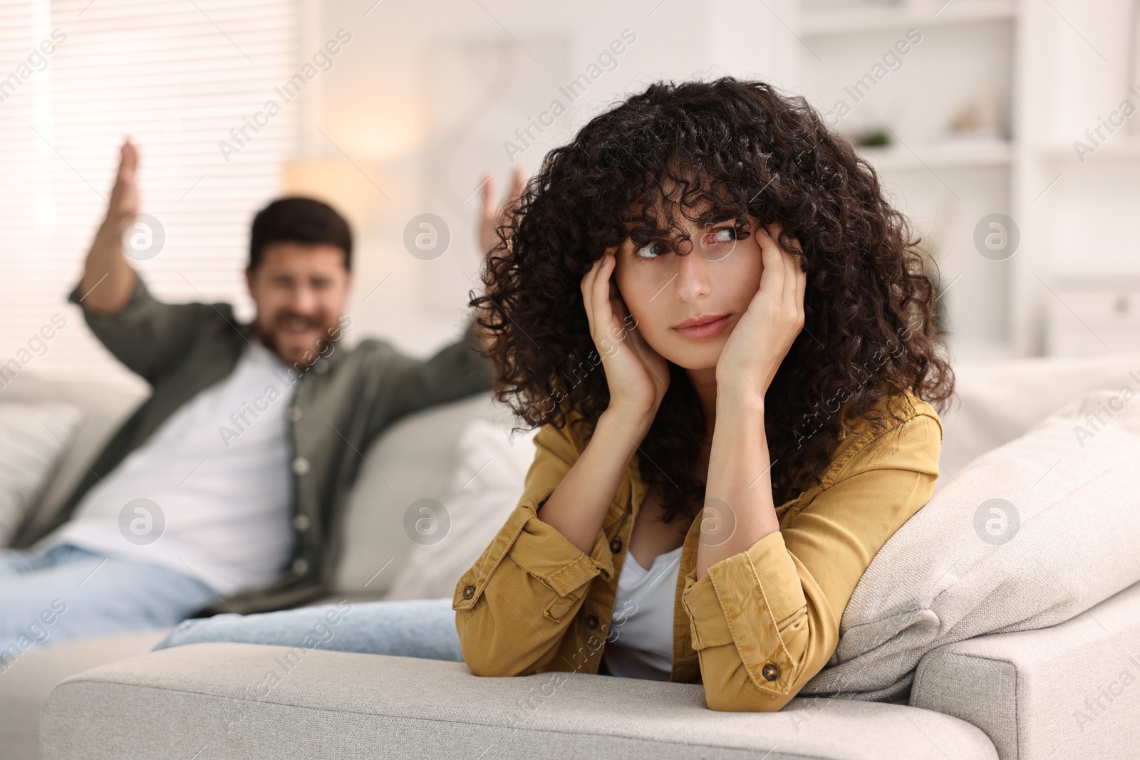 Photo of Couple having quarrel on sofa at home, selective focus. Relationship problems