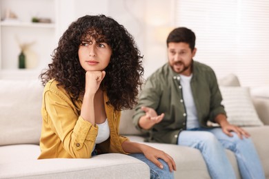 Photo of Couple having quarrel on sofa at home, selective focus. Relationship problems