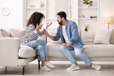 Photo of Emotional couple arguing on sofa at home. Relationship problems