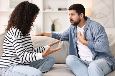 Photo of Emotional couple arguing on sofa at home. Relationship problems