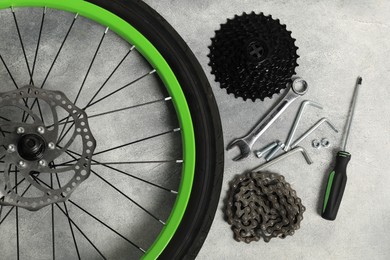 Photo of Parts of bicycle and tools on grey background, flat lay