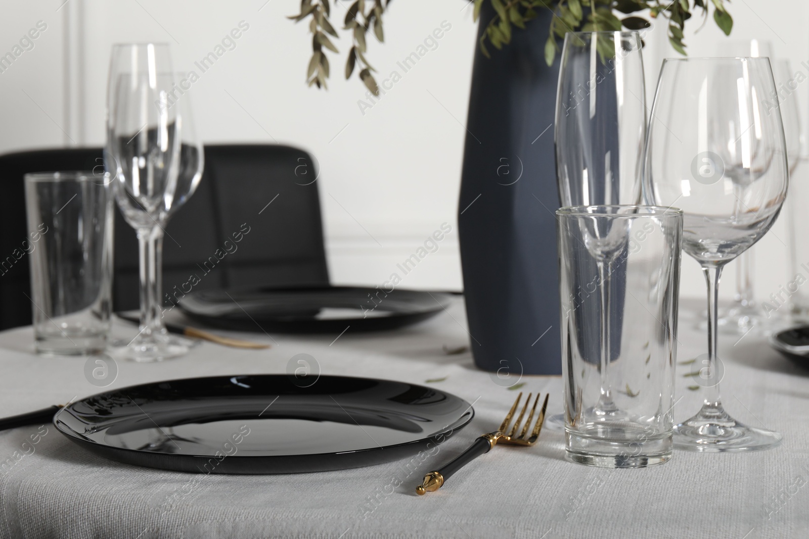 Photo of Stylish table setting with black dishware in dining room