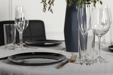 Photo of Stylish table setting with black dishware in dining room